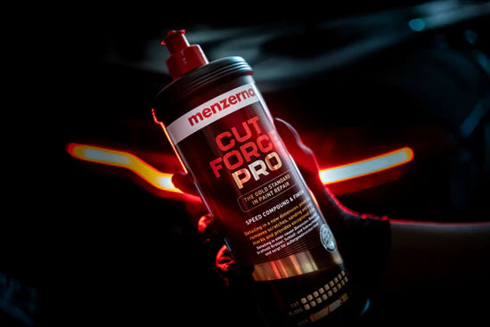 Menzerna Cut Force Pro car polish bottle held by a hand with a dark background