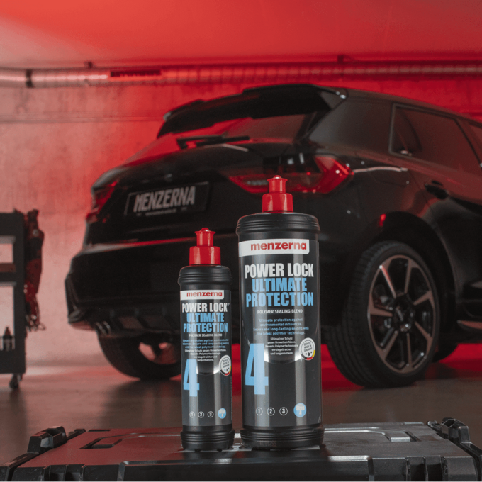 Menzerna car care products with a black car in a garage setting